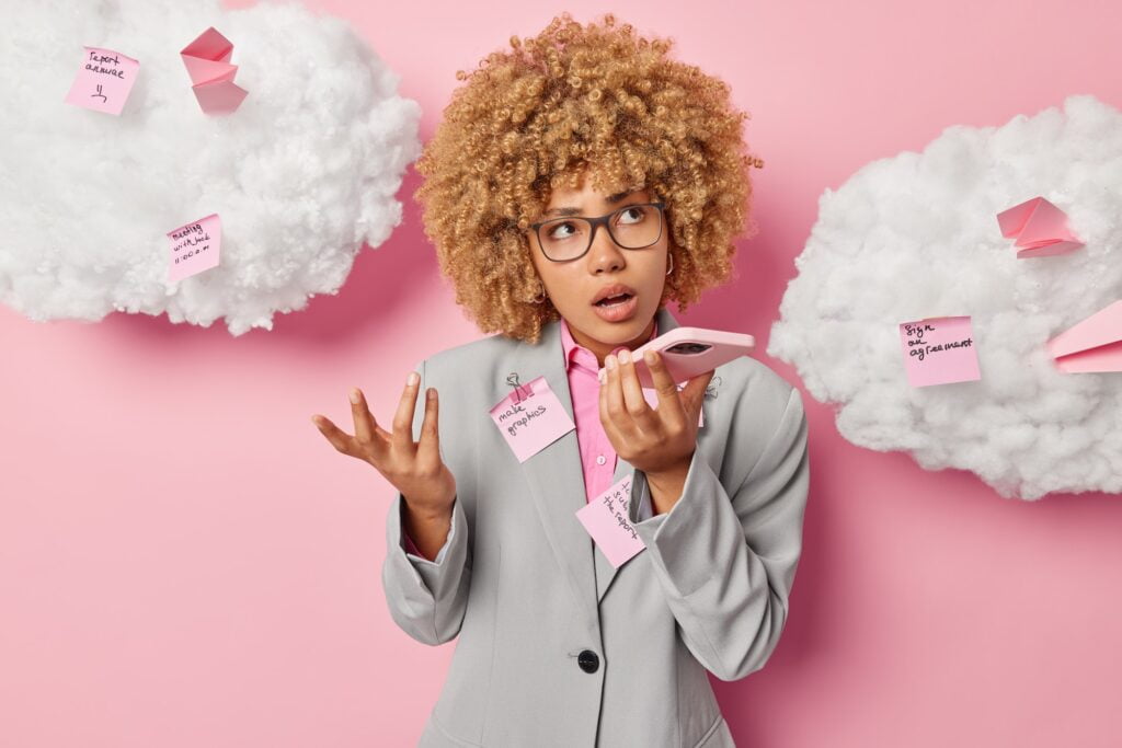 Female business professional records voice message via smartphone looks confused doesnt know what to